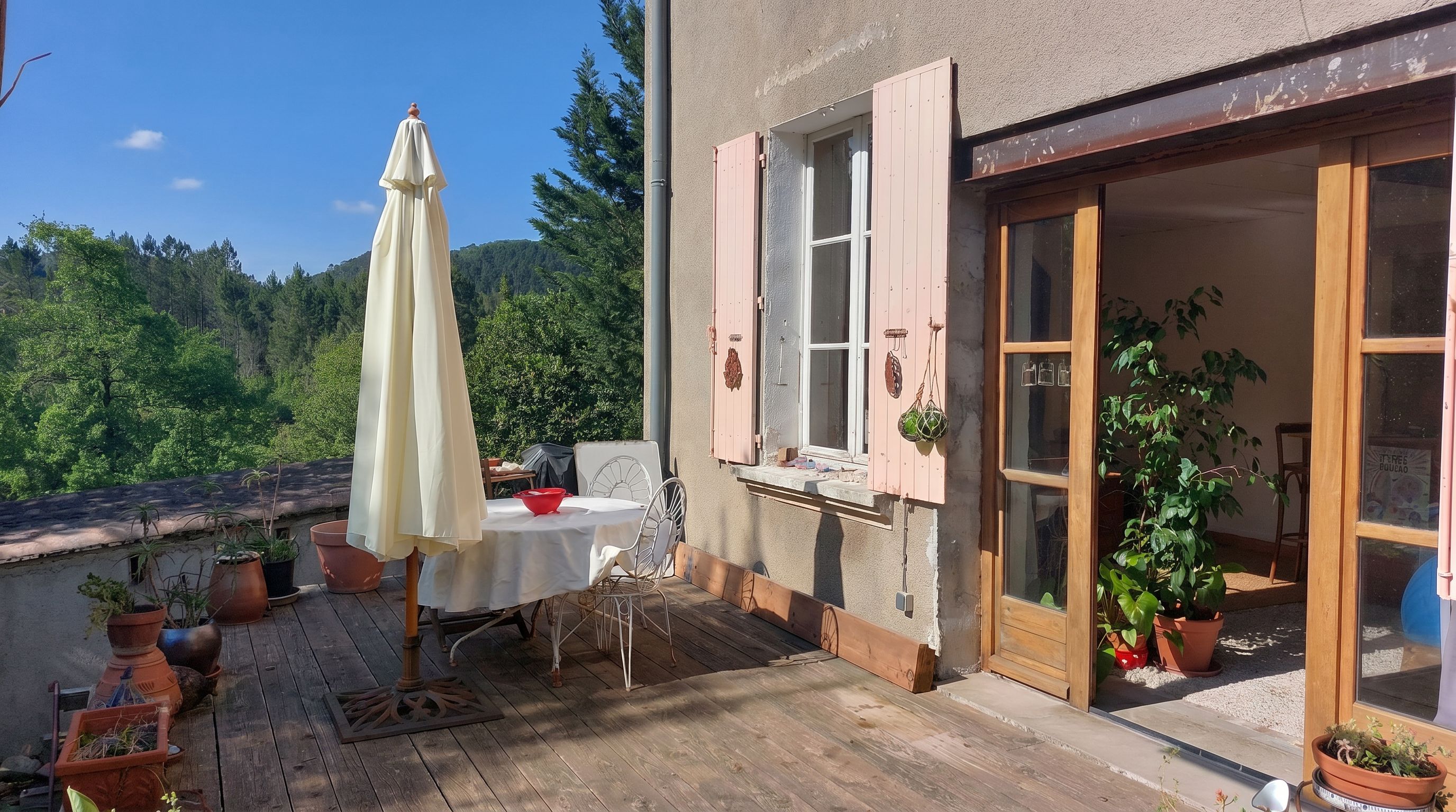 Terrasse en bois sous la pergola de glycine, vue sur la vallée